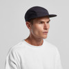 A black cap with a flat peak, featuring mesh panels for breathability. The model is wearing a white T-shirt.