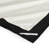 A tea towel featuring a black bottom edge and cream top, with decorative white stitching along the seams.