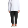 Black track pants for kids, featuring an elastic waistband and cuffs, paired with a white long-sleeve top and casual shoes.