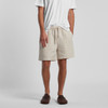 Linen shorts in a light beige colour, featuring an elastic waistband and side pockets, worn with a white t-shirt.