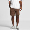 Brown dress shorts with side pockets and a drawstring waist, worn with a plain white shirt and grey sneakers.