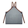 A denim apron in blue with brown straps, featuring a pocket at the front and a logo.