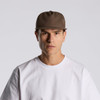 A brown cap with a structured design, featuring a logo, worn by a model in a white t-shirt.