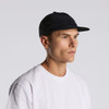 A black trucker cap with mesh panels and a curved brim, worn by a person in a white t-shirt.