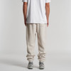 Relax Track Pants in a light beige hue, featuring a relaxed fit and cuffed ankles. The model is shown from behind.