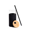 A drink bottle featuring a clear glass body, black silicone sleeve, bamboo lid, and a black straw.