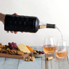 A drink bottle in a matte black wine cooler, pouring rosé into two glasses, accompanied by a cheese and snack platter.