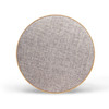 A round Bluetooth speaker in a light grey fabric finish with a wooden border. It features a logo.