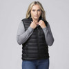 A woman wearing a black padded baffle vest over a grey long-sleeve top, with her hands at the collar.