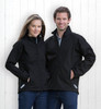 A couple stands in front of a white wooden background, wearing black soft shell jackets. The jackets feature a logo.