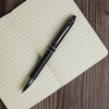 A Columbia Aluminium Pen rests on an open notebook with lined pages.