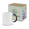 A coffee mug with a white body and black handle, displayed alongside a decorative box featuring floral designs.