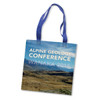 A cotton tote bag in blue and white features a scenic mountain landscape with two fabric handles. It has a logo.