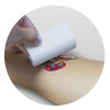 A hand applying a temporary tattoo foil to an arm, featuring a colorful design. The tattoo measures 51mm x 51mm.