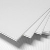 A stack of white core flute sheets with a ribbed texture, displaying multiple layers.