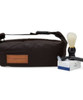 A dark brown toiletry bag with a handle, a shaving brush, and a box of shaving cream.