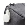 A grey bag with a white keyring attachment prominently displayed on the zipper.