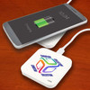 A square wireless charger in white with a logo, placed beneath a smartphone displaying a charging battery icon.