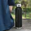 A drink bottle with a sleek black exterior and a stainless steel cap, featuring an engraved logo that reads "FINANCE."