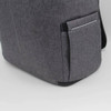 A grey backpack with a side pocket and a logo. The fabric has a textured appearance, adding to its style.