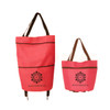 A pink collapsible shopping trolley bag with brown straps, featuring a logo on the front.