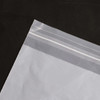 A clear, eco-friendly biodegradable self-adhesive bag with a sealable top edge, resting on a dark surface.
