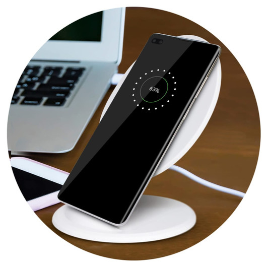 A wireless charging stand in white with a smartphone displaying charging progress, placed on a wooden surface.