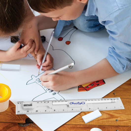 A stationery set featuring pens, a ruler, and erasers on a drawing surface, with children engaged in artwork.
