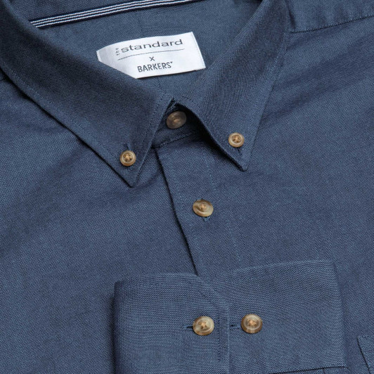 A blue button-up shirt with a chest pocket and brown buttons, featuring a collar and a brand logo.
