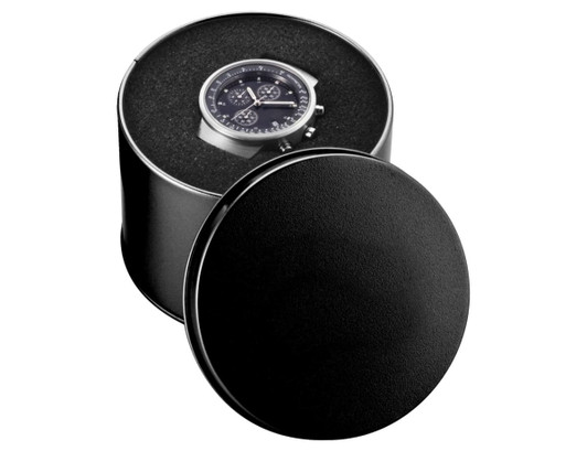 A round black watch case with a sleek watch displayed inside, featuring a dark watch face and metallic details.