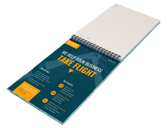 A top-bound A5 notebook with a spiral binding, featuring blank pages and a colourful promotional cover.