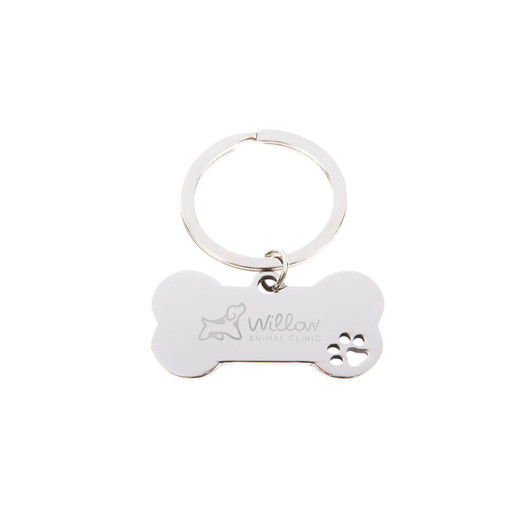 A silver dog bone keytag featuring a paw print design and an engraved logo.