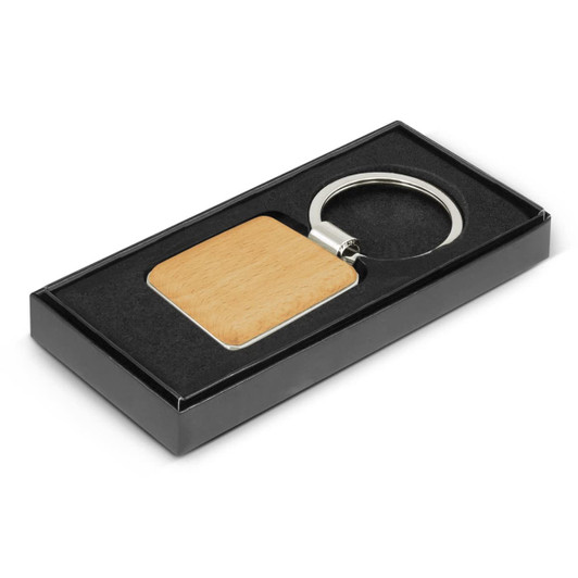 A square wooden key ring with a metal ring, presented in a black gift box with a velvet-like interior.