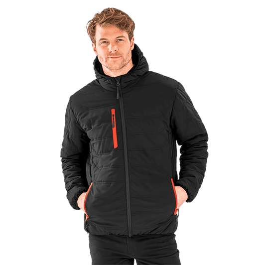 A padded winter jacket in black with orange accents, featuring a zippered front and pockets, worn by a smiling model.
