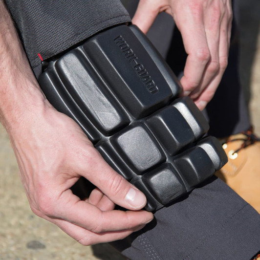 Knee protectors in black being fitted onto a person's leg. The product features a textured design for added protection.