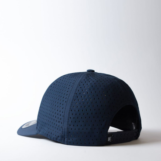 A navy blue snapback cap featuring a curved peak and perforated design, with a branding logo on the back.