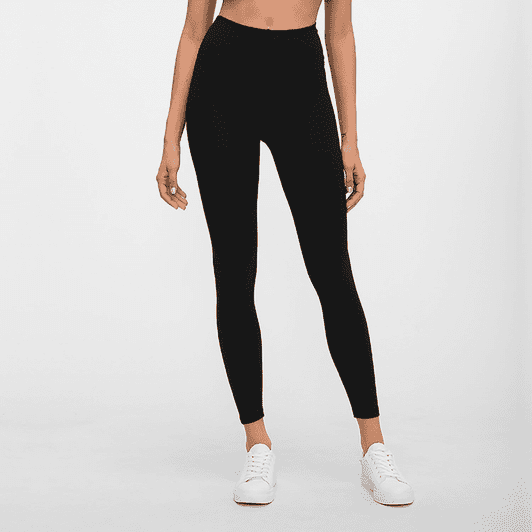 Black high-rise training full tights made from a flexible material, styled with a sleek fit and paired with white sneakers.