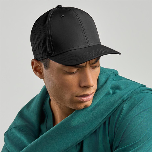 A black cap is displayed, featuring a rounded crown and a curved visor, worn by a model in a teal hoodie.