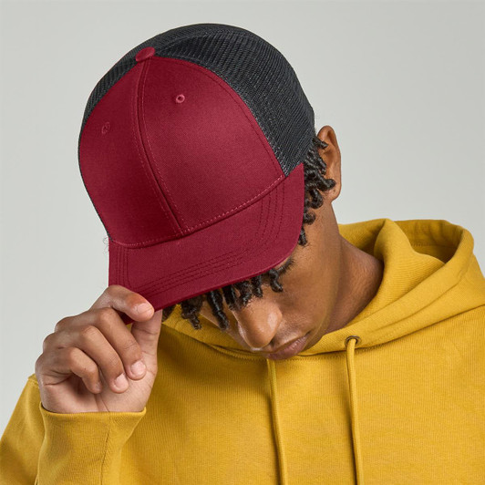 A maroon trucker cap with a black mesh back, worn by a person in a yellow hoodie. The cap features a logo.