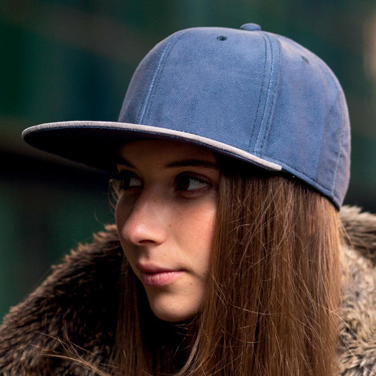 A blue cap worn by a person with long hair, featuring a flat brim and a logo on the front.