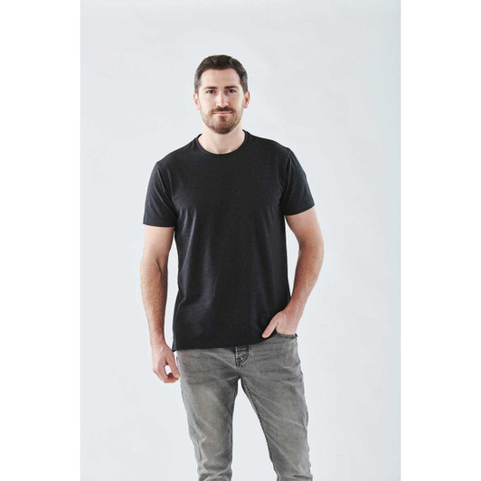 A model wearing a black short sleeve tee, paired with grey jeans, standing against a light background.