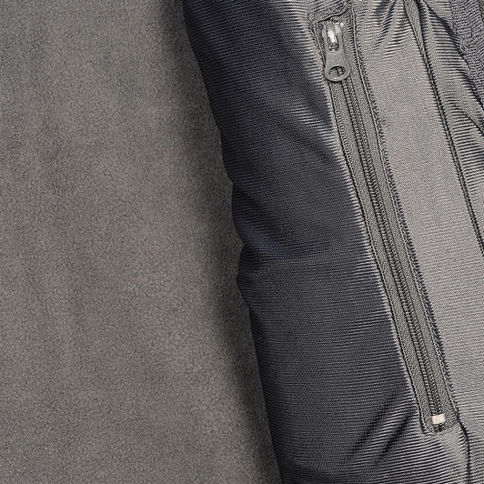 A close-up of a women's softshell jacket in black and grey, featuring a zippered pocket.
