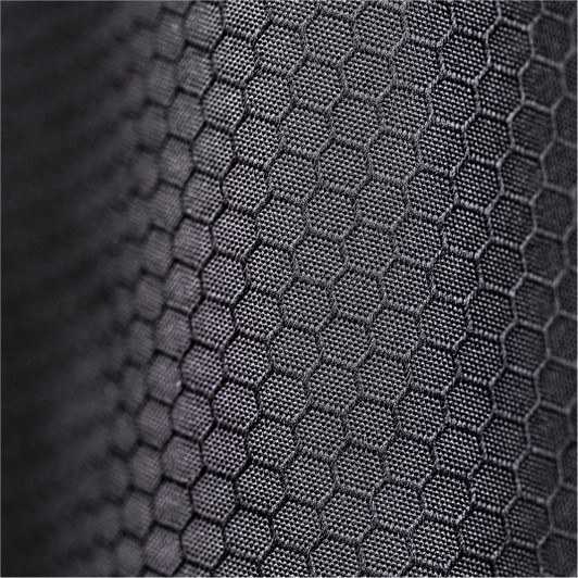 A close-up of textured black fabric with a hexagonal pattern, featuring a subtle sheen.