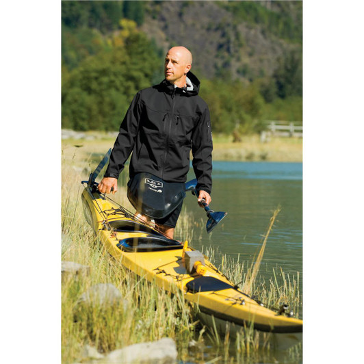 A man stands by a river wearing a black Men's Epsilon H2Xtreme Shell jacket, near a yellow kayak.