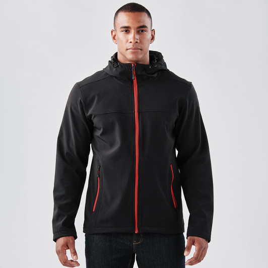 A black softshell hoody with red accents, featuring a zip front, zip pockets, and a hood. Includes branding.