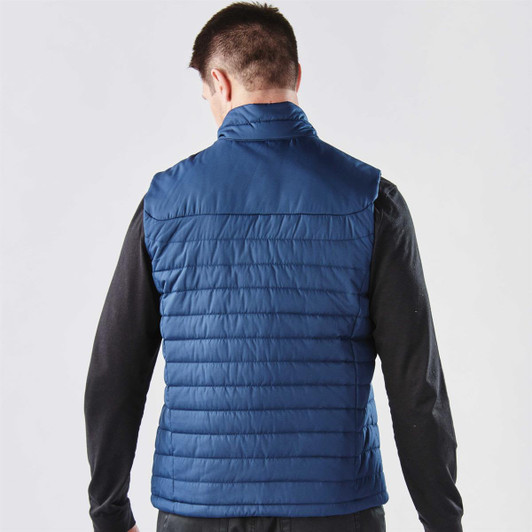 A navy blue quilted vest with a high collar, viewed from the back, featuring a subtle logo detail.