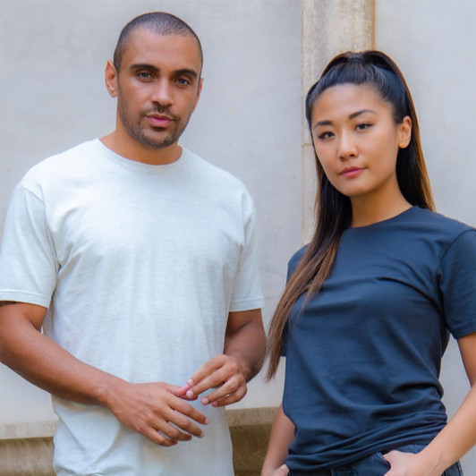 A light grey men's cotton crew t-shirt and a black women's cotton crew t-shirt on models. Both shirts have logos.