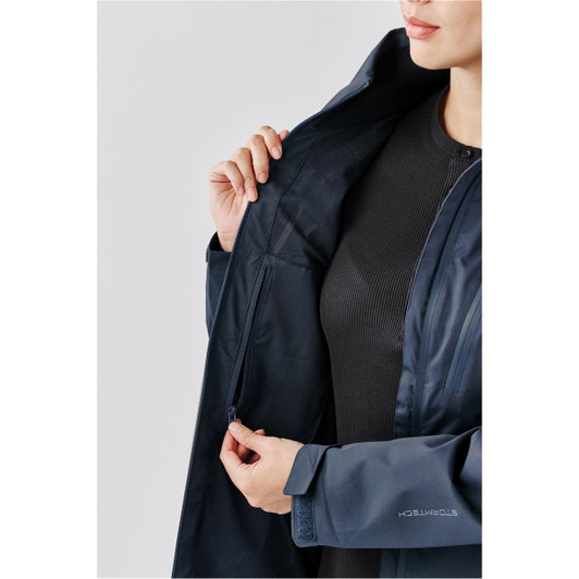 A dark navy lightweight shell jacket with a zippered pocket, showcased on a model. The jacket features a logo on the sleeve.