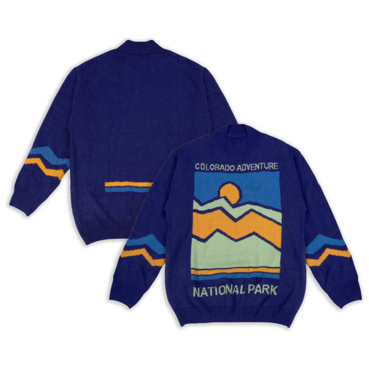 A blue knitted jumper featuring a mountain and sun design in yellow and orange with a logo.