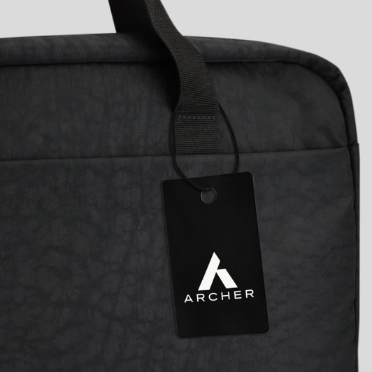 A black laptop bag featuring a top handle and a tag with a logo. The material has a textured finish.